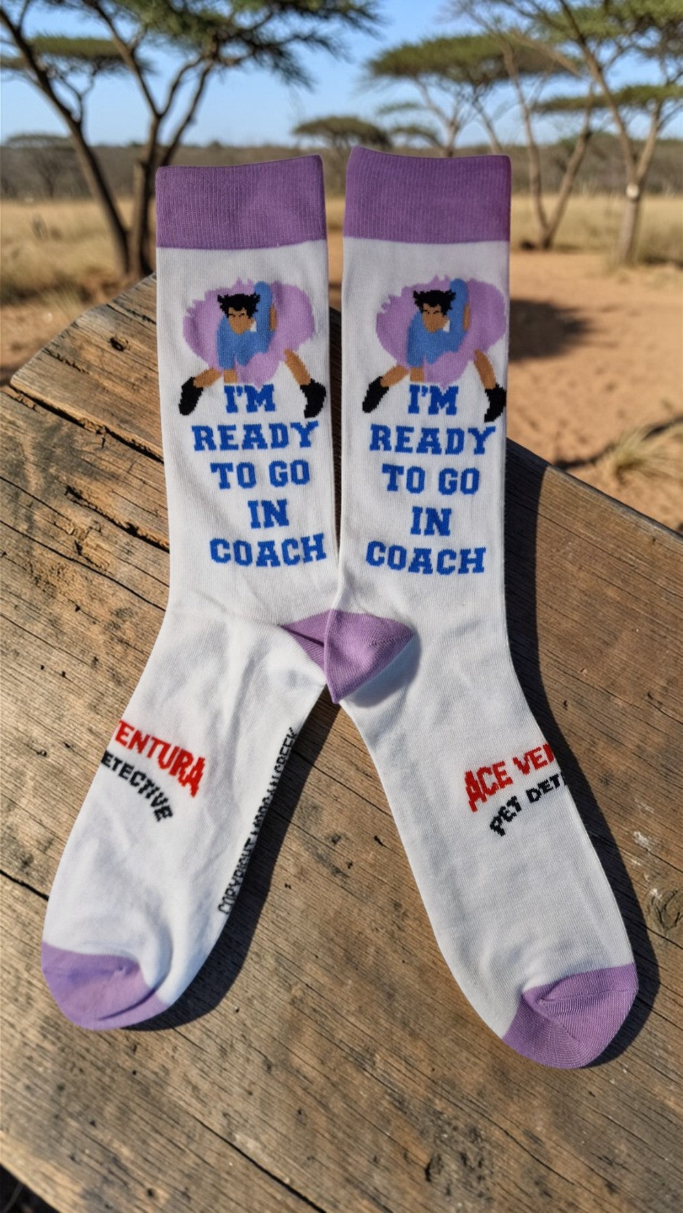 Pair of socks with a character design and text on a wooden surface with a natural background