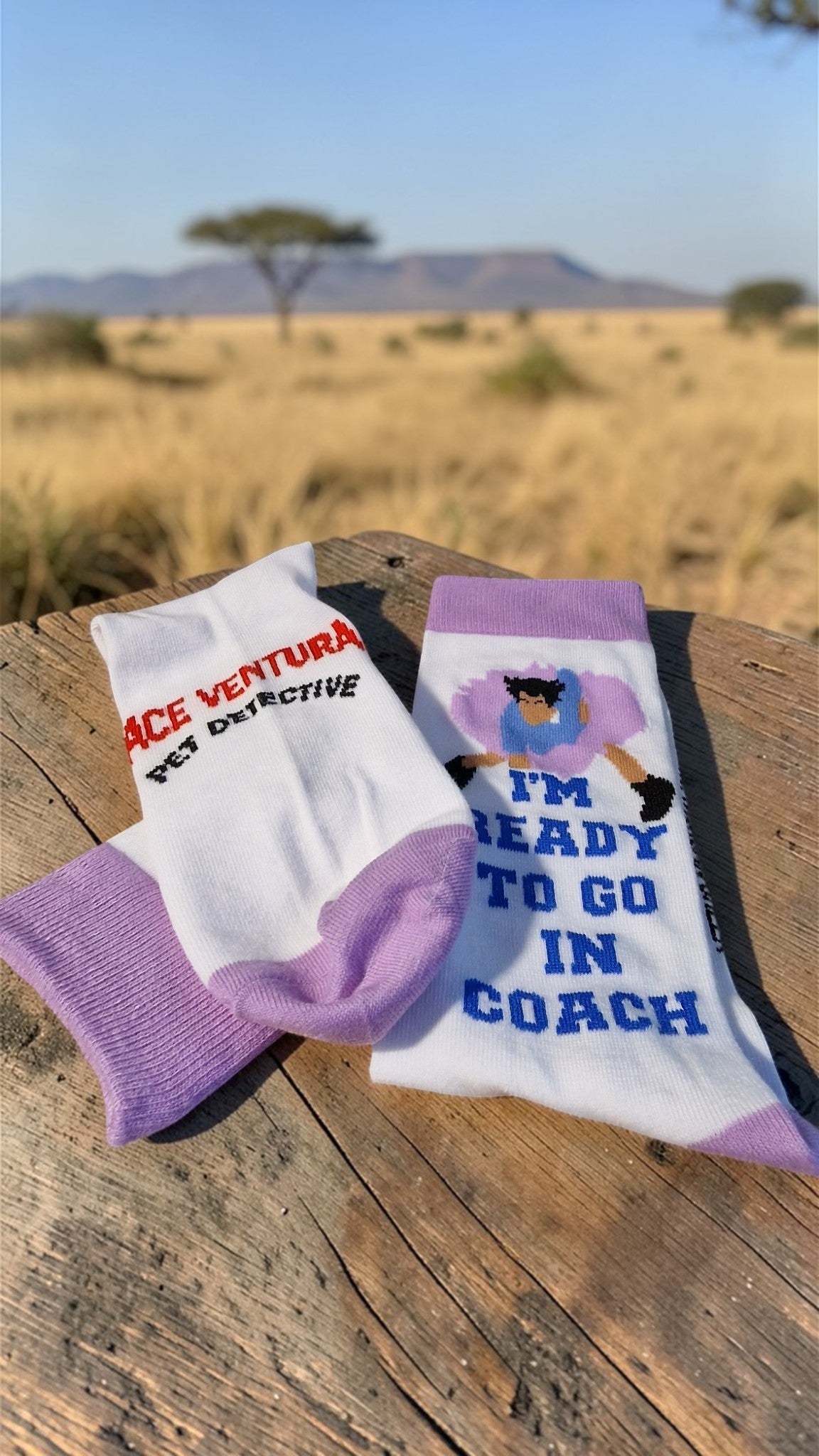 Two pairs of socks with text on a wooden surface with a desert landscape in the background