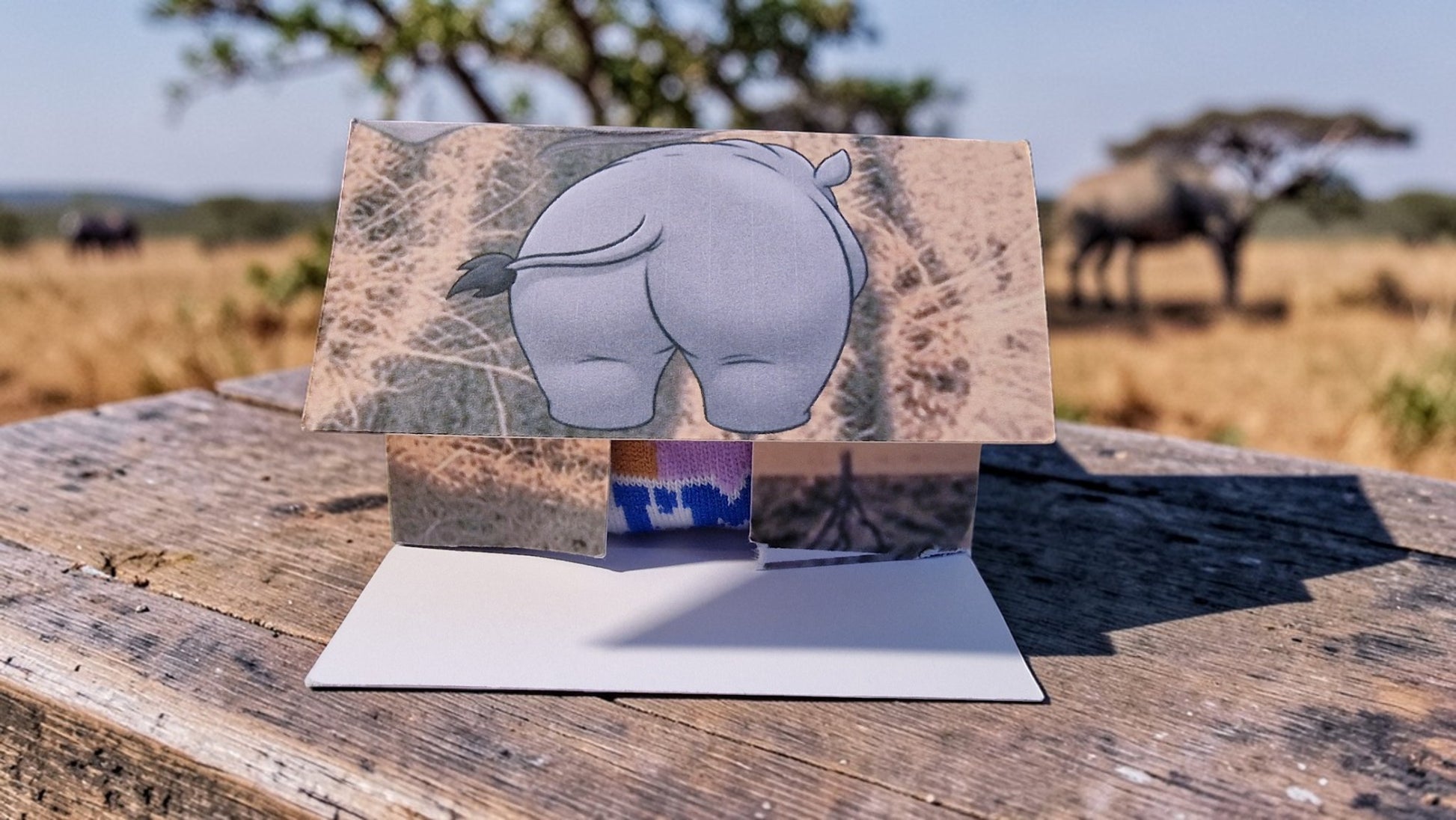 Card with a rhino illustration on a stand against a natural background