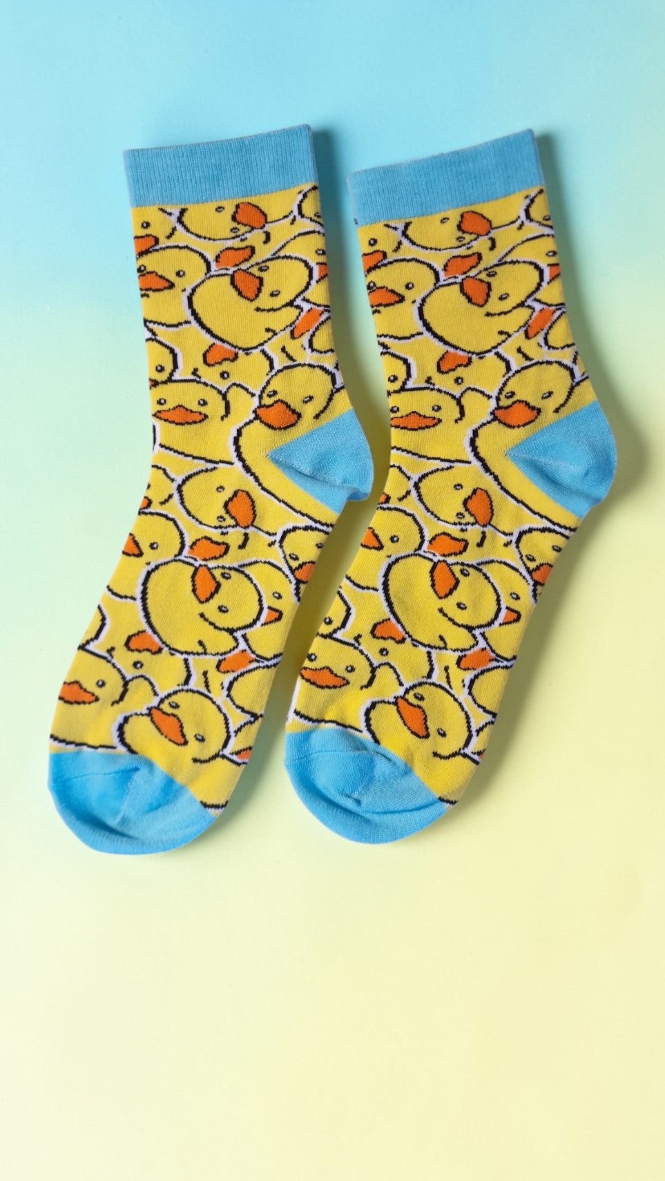 Two socks with yellow rubber duck pattern on a gradient background
