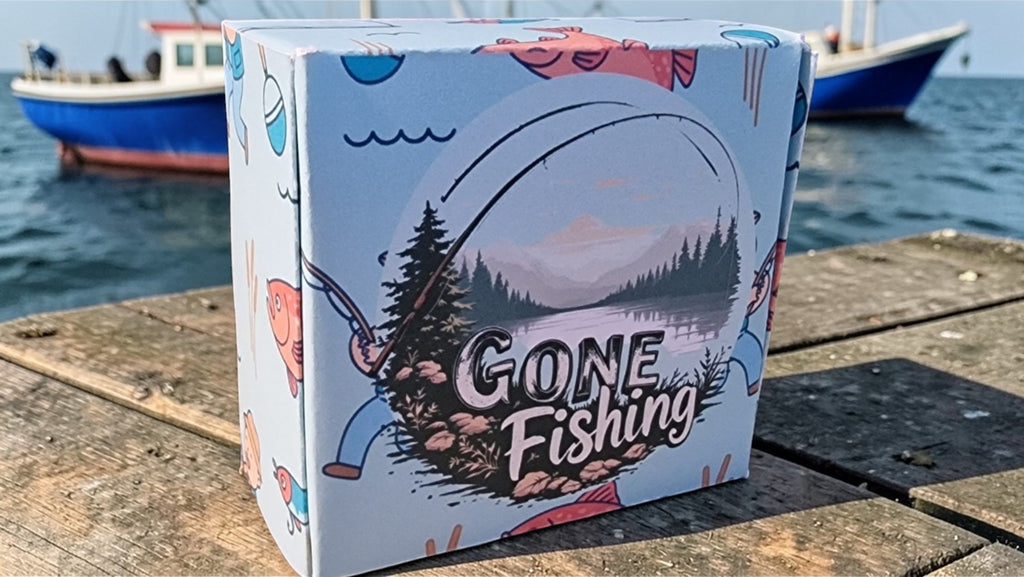 Box with 'Gone Fishing' design on a wooden surface by water