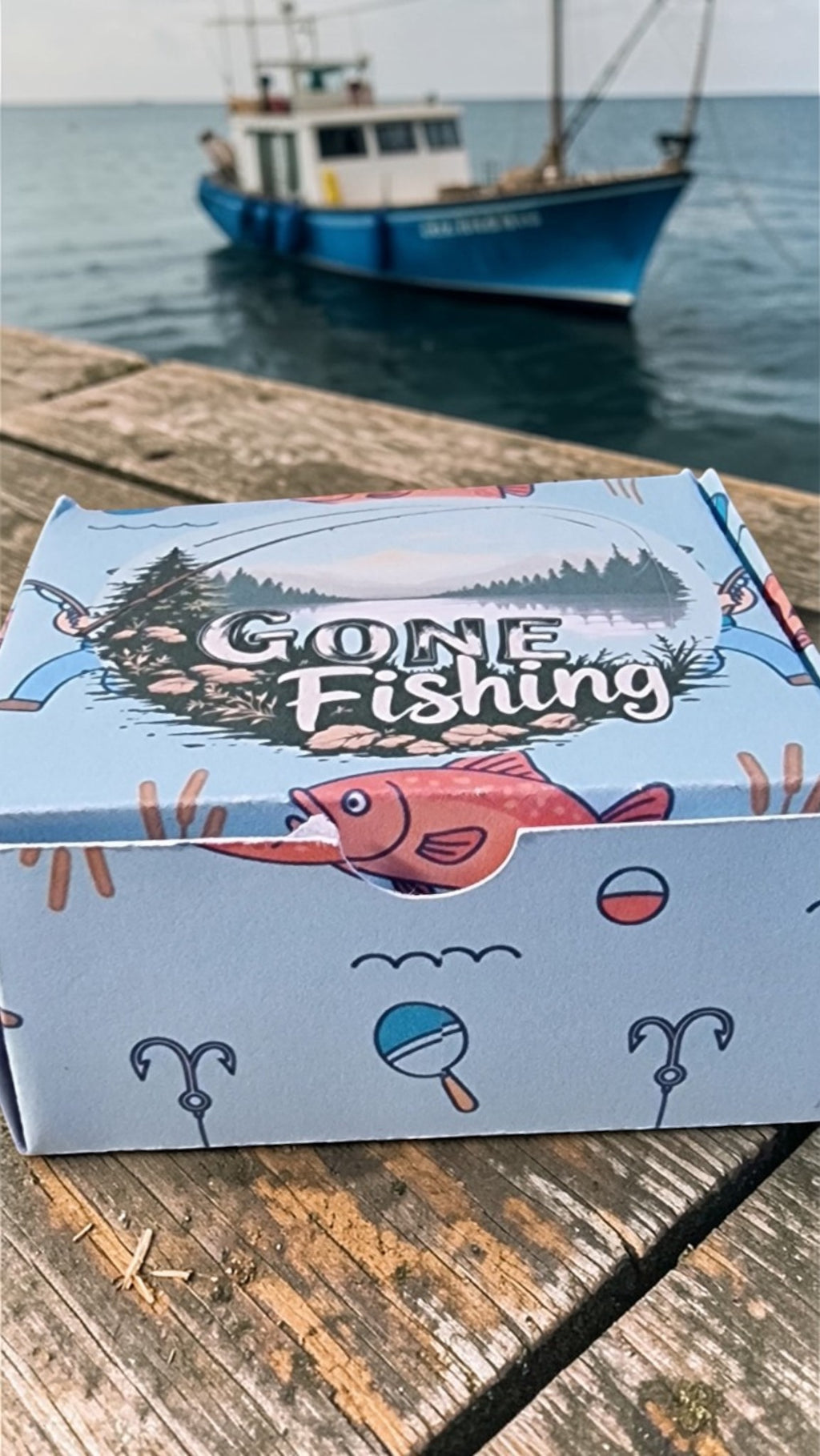 Box with 'Goose Fishing' branding on a wooden surface with a boat in the background.