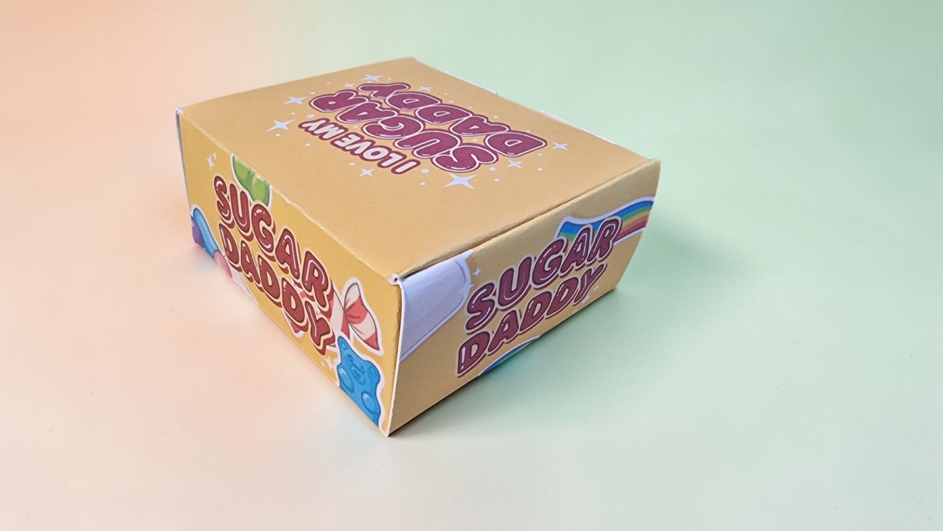 Box of 'Sugar Daddy' candy with colorful text on a gradient background