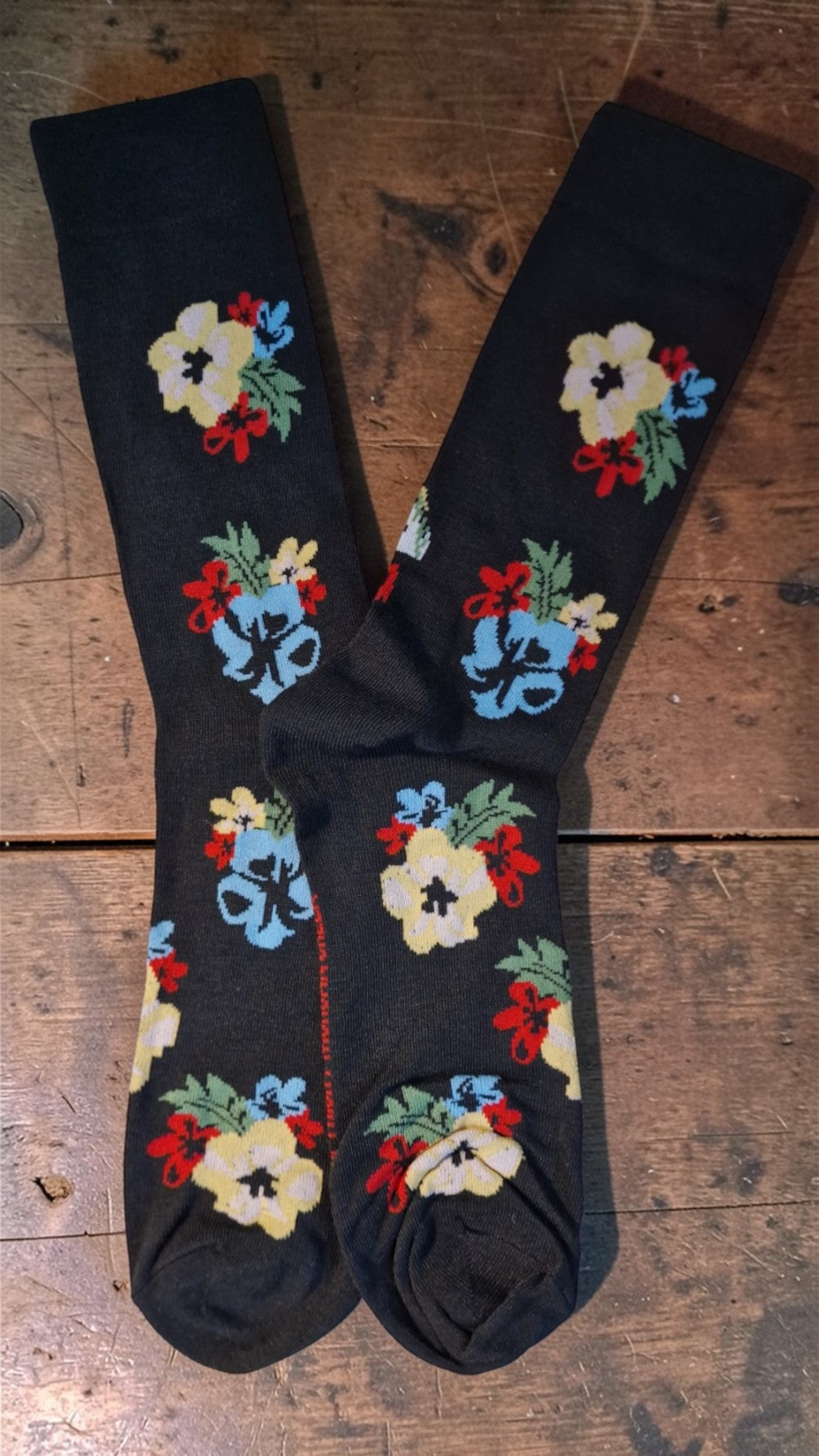 Black socks with colorful floral patterns on a wooden surface