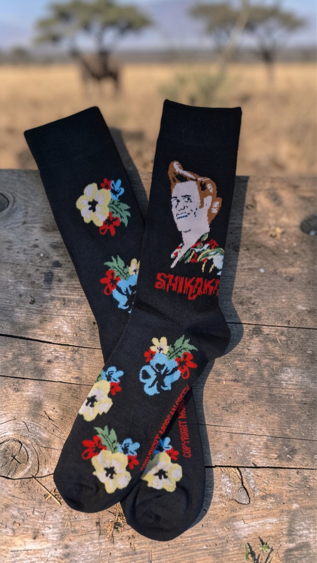 Black socks with colorful designs and text on a wooden surface with a natural background