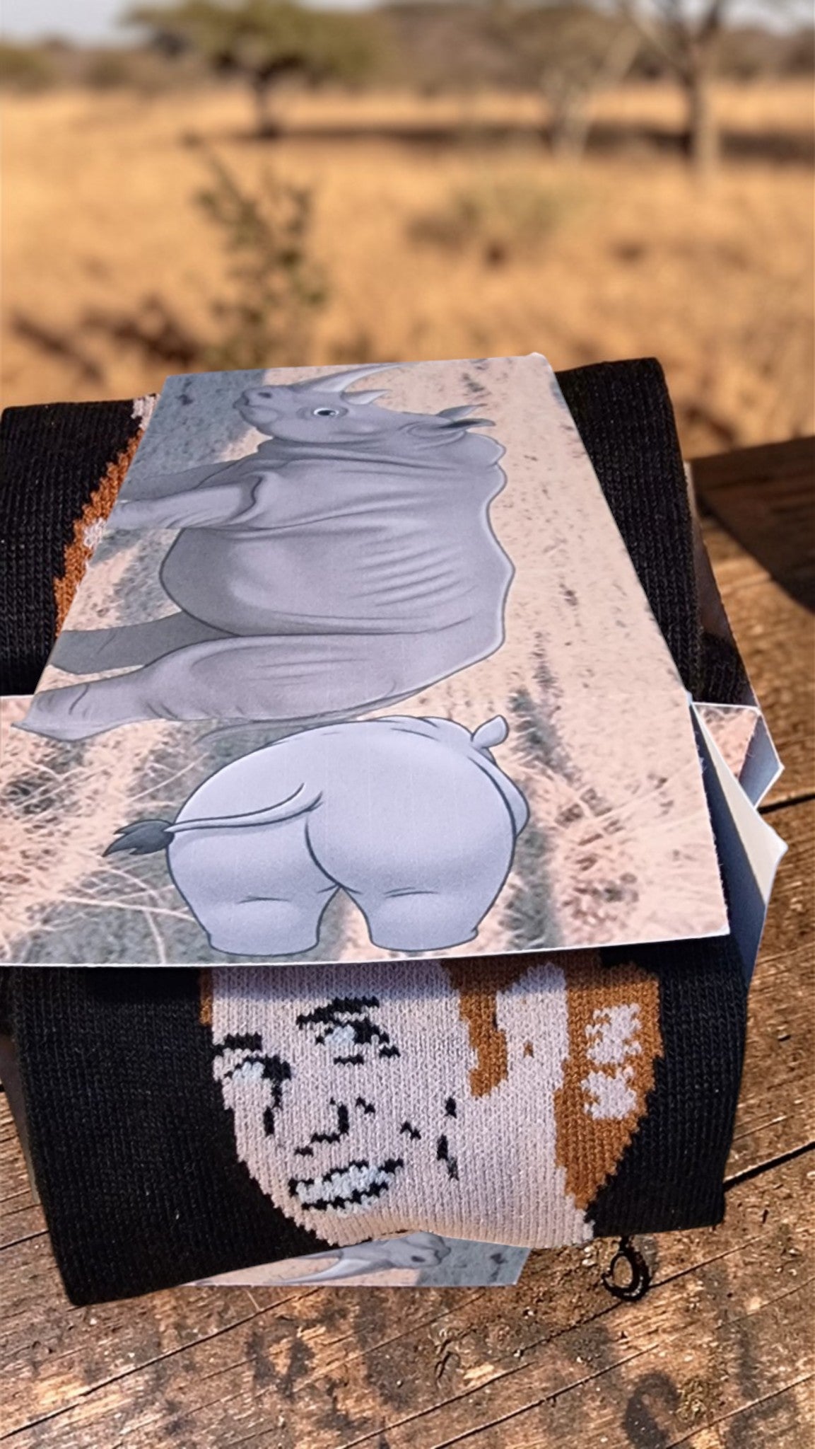 Pair of socks with rhino design on a wooden surface with natural background
