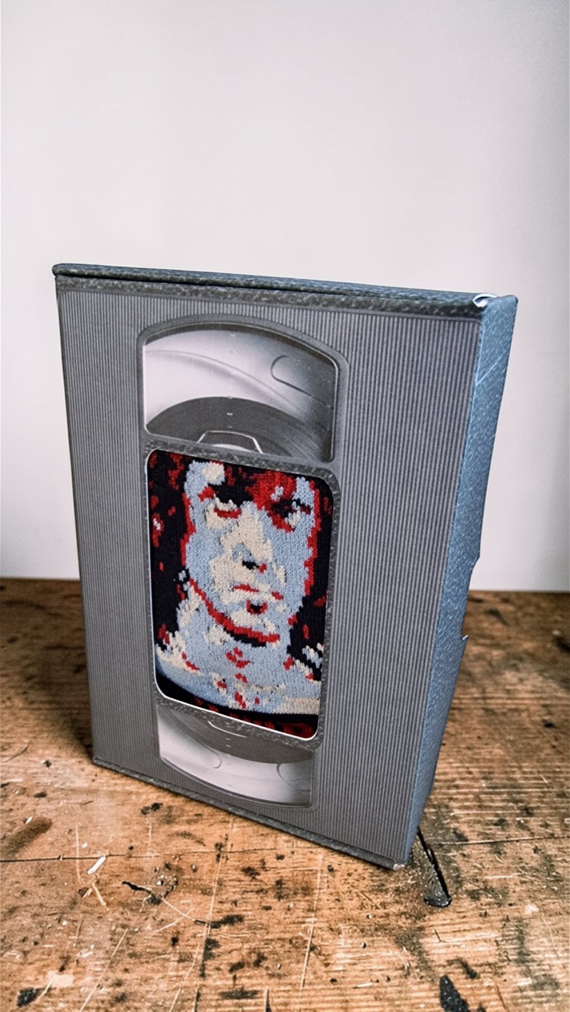 VHS tape with a pixelated face design on a wooden surface
