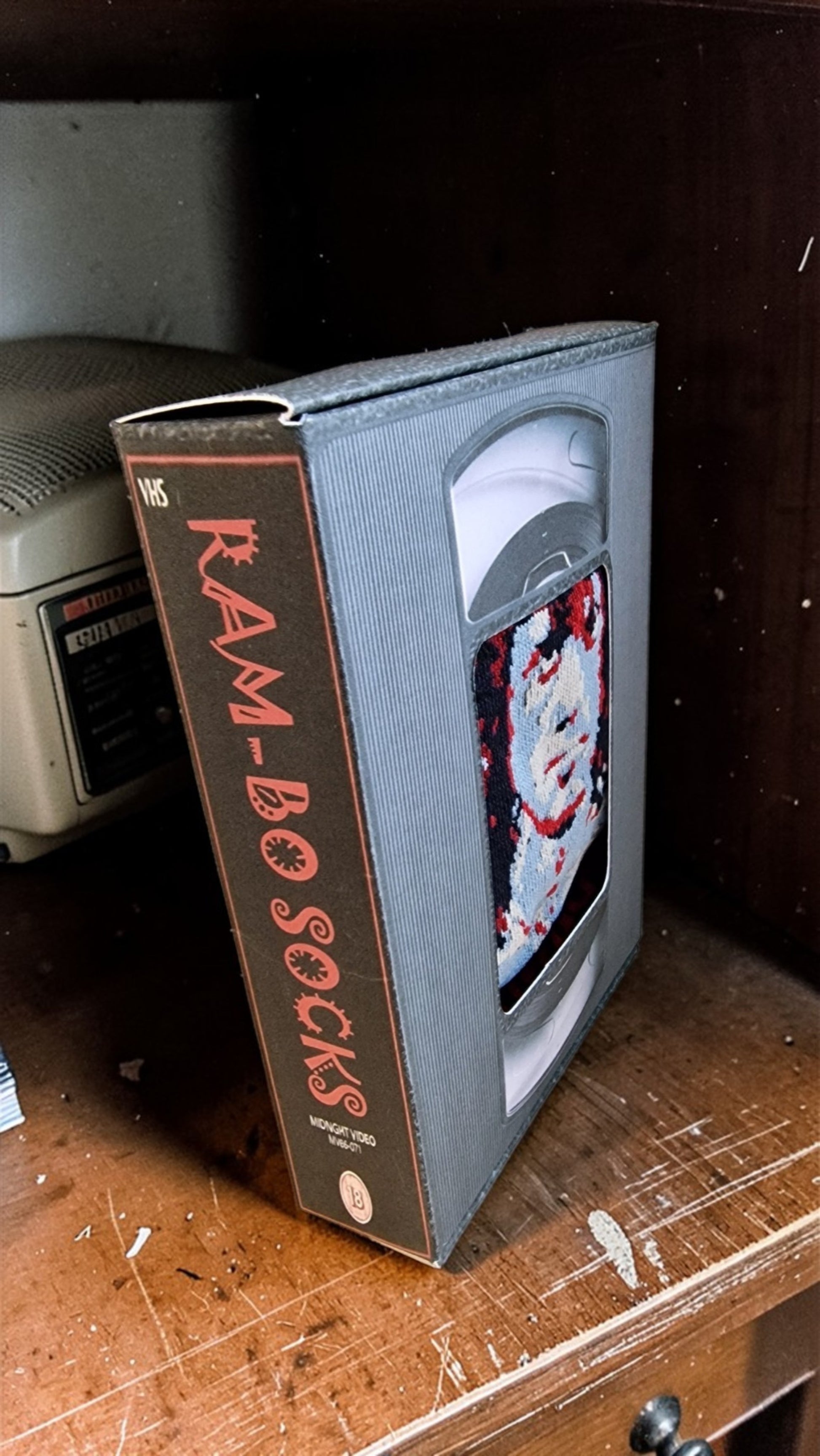 VHS tape with 'Ram-Bo Socks' packaging on a wooden surface