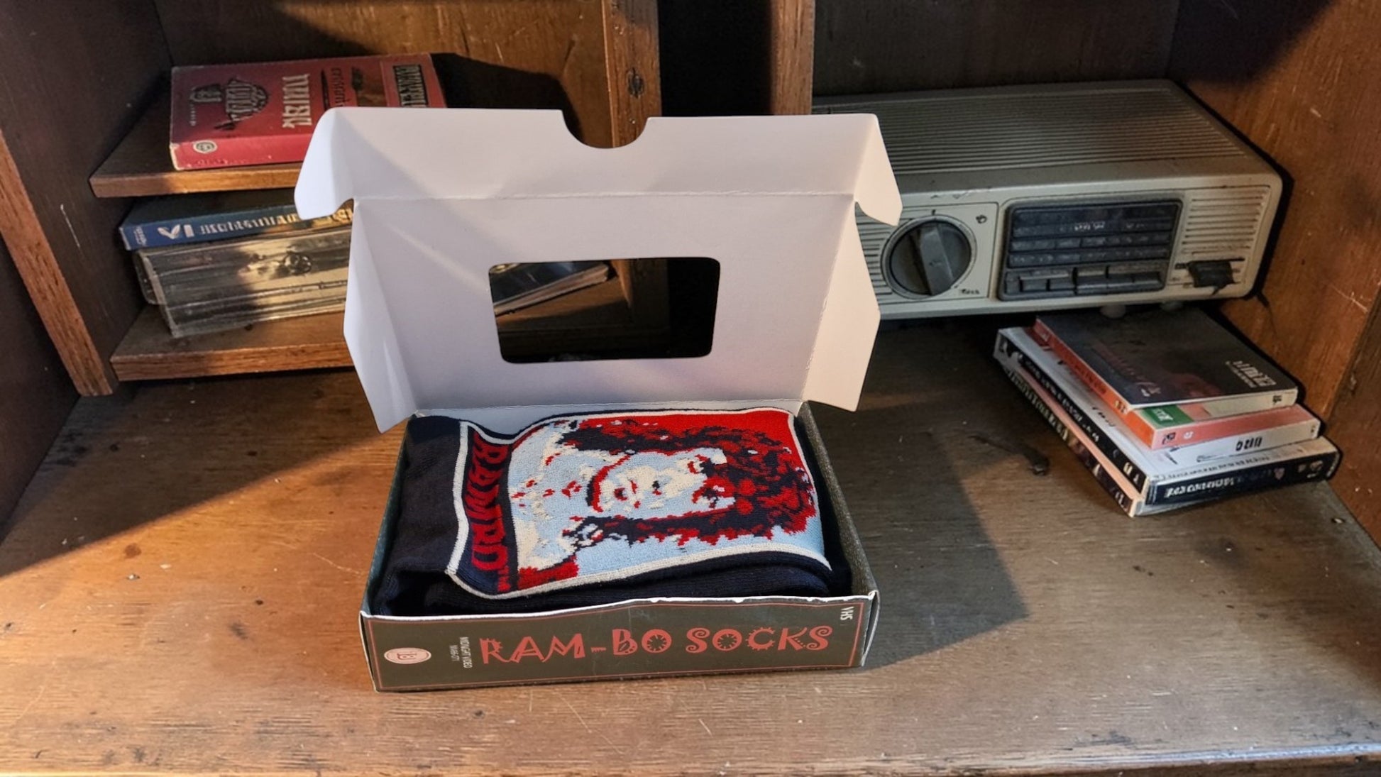 Box of Ram-Bo socks on a wooden surface with vintage radio and books in the background