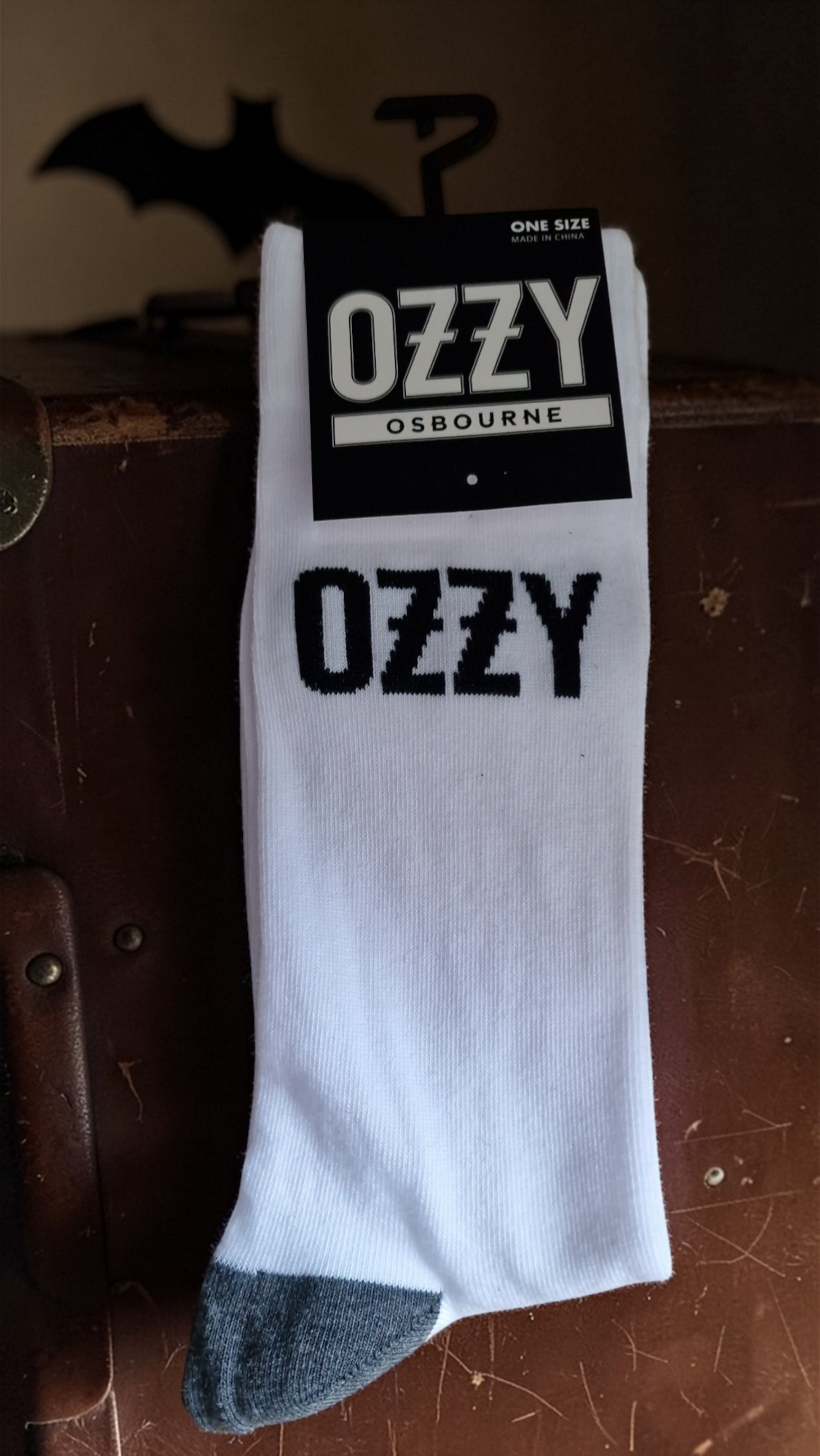 White sock with 'Ozzy' branding on a wooden surface