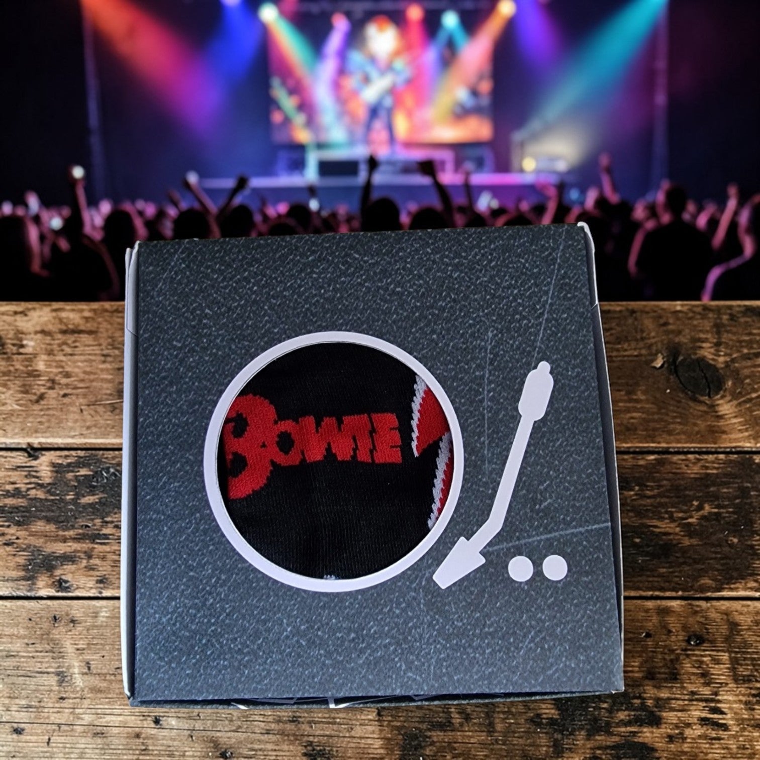 Product packaging with 'Bowie' design on a wooden surface with concert background
