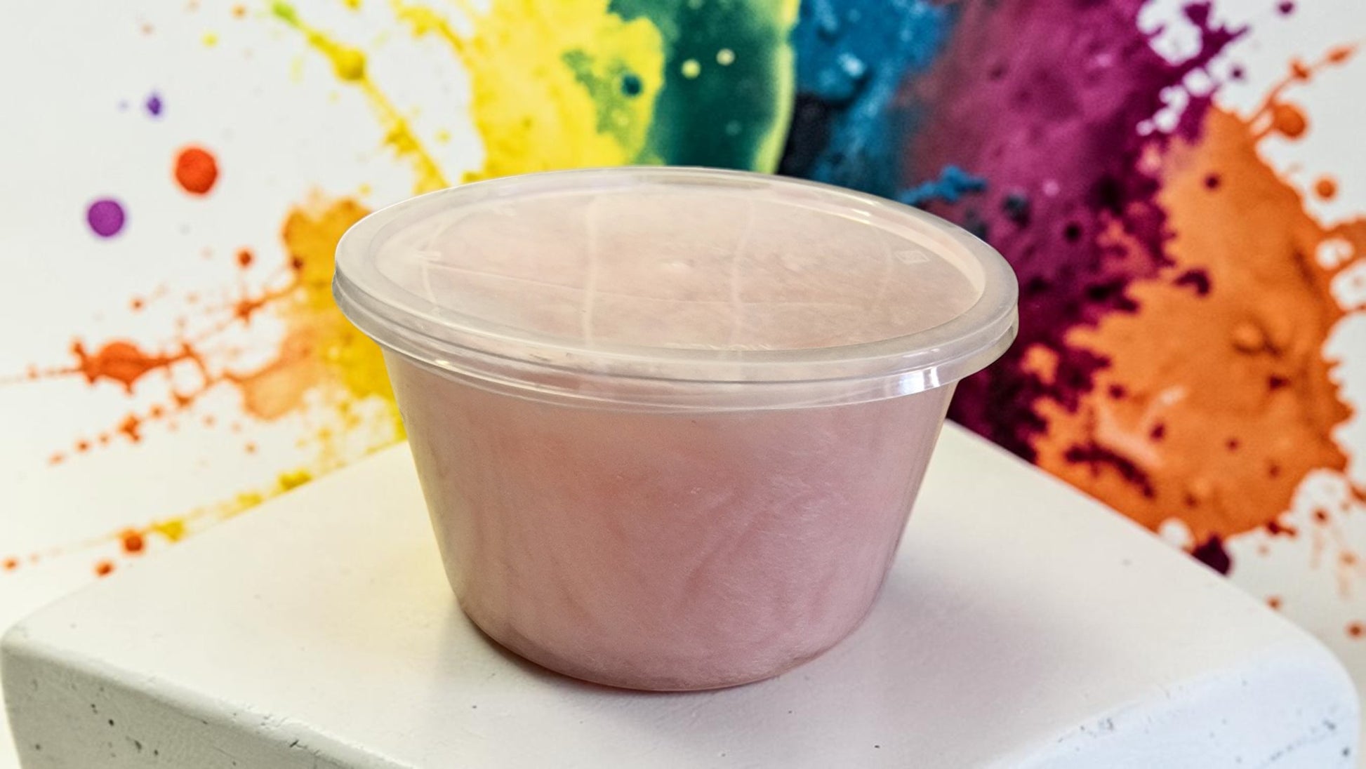 Pink container on a white surface with a colorful abstract background