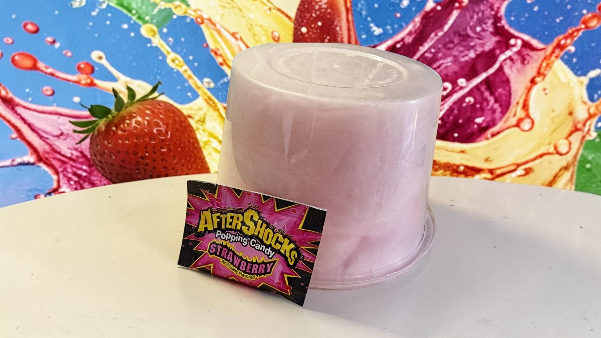 Pink cone with a colorful AfterShocks packaging card against a vibrant, abstract background.