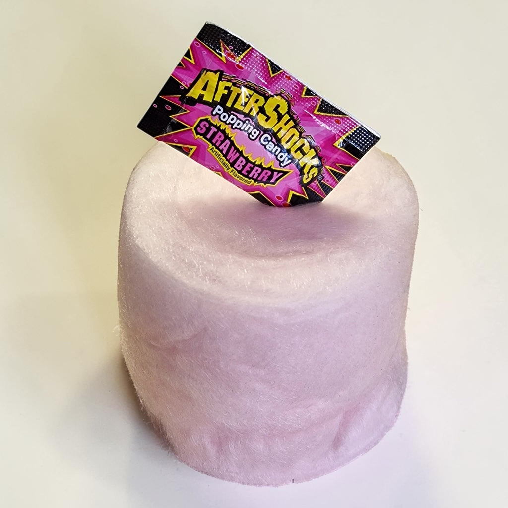 Pink cotton candy with a 'Aftershock' candy package on top against a white background