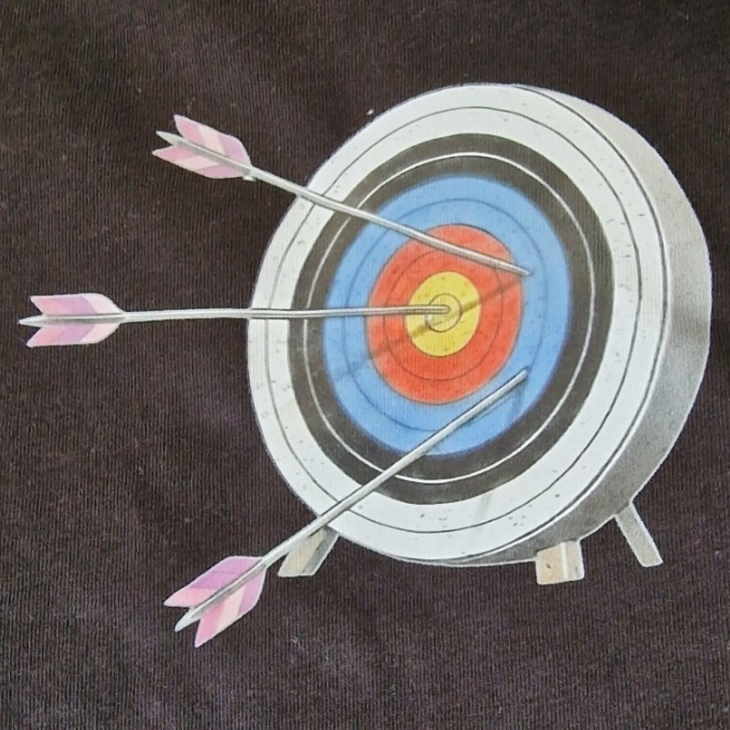 Archery target with three arrows hitting the bullseye on a dark background