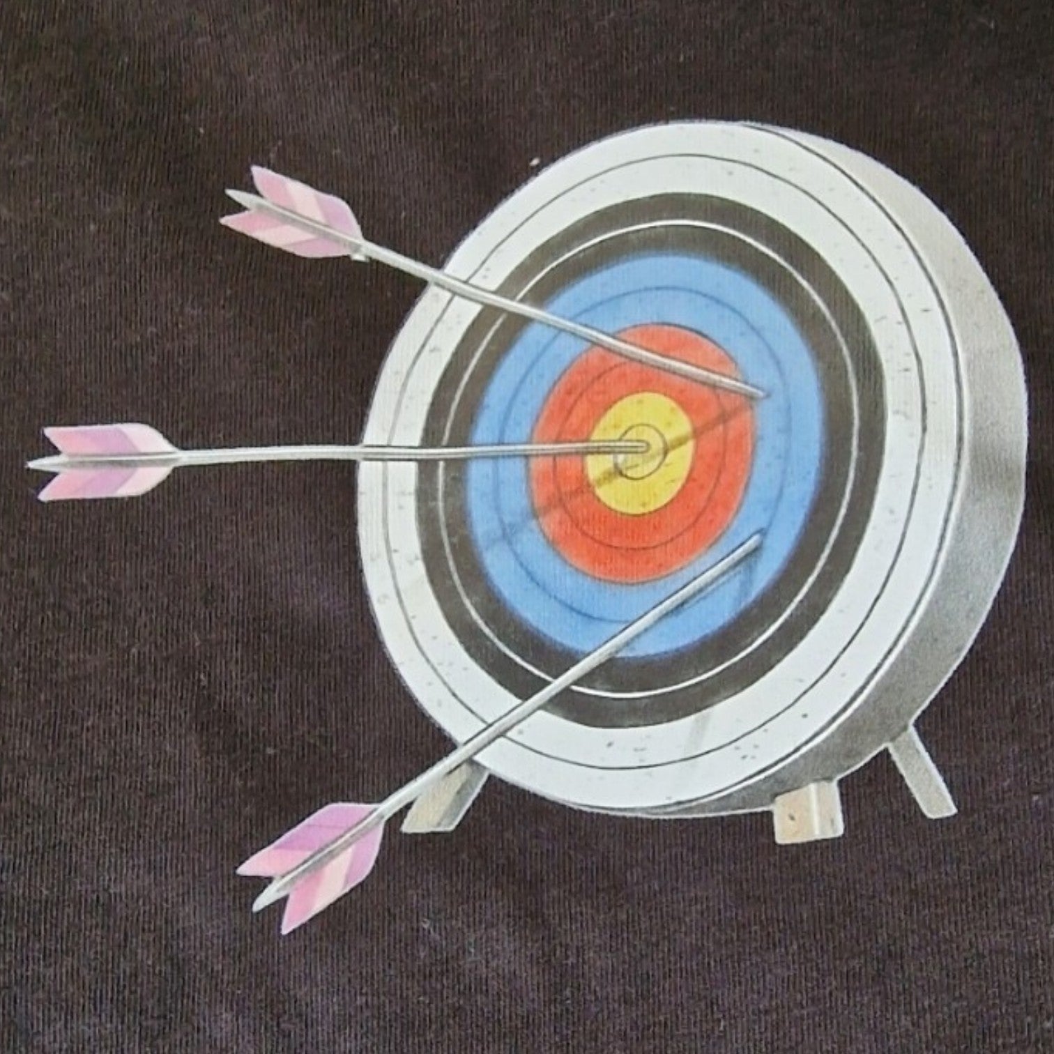 Archery target with three arrows hitting the bullseye on a dark background