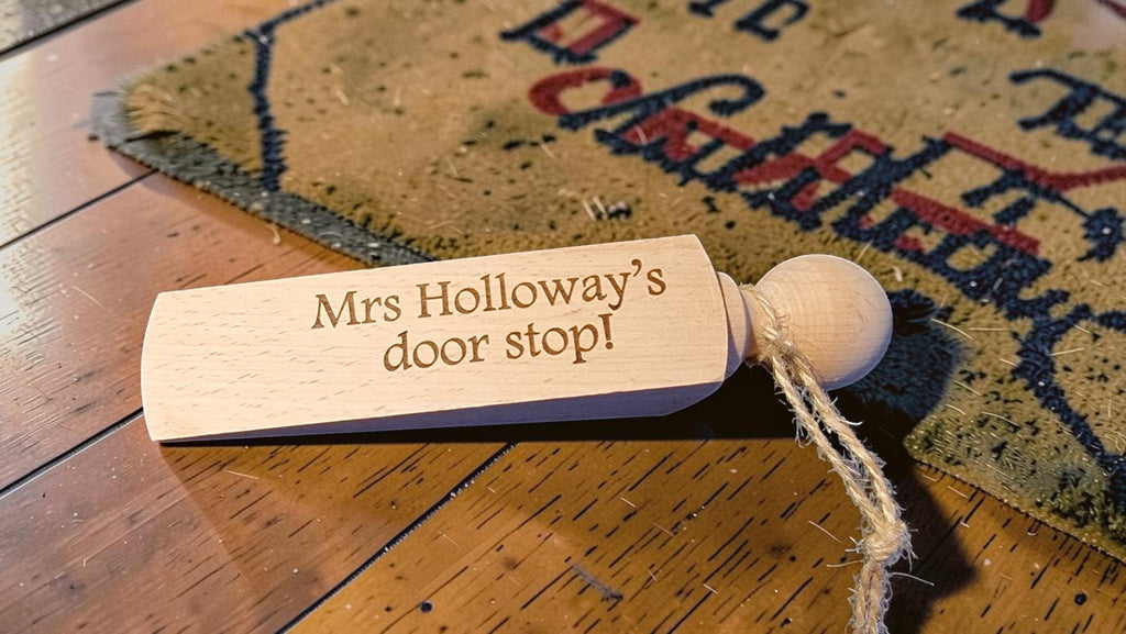 Wooden door stopper with 'Mrs Holloway's door stop' engraving on a wooden floor.