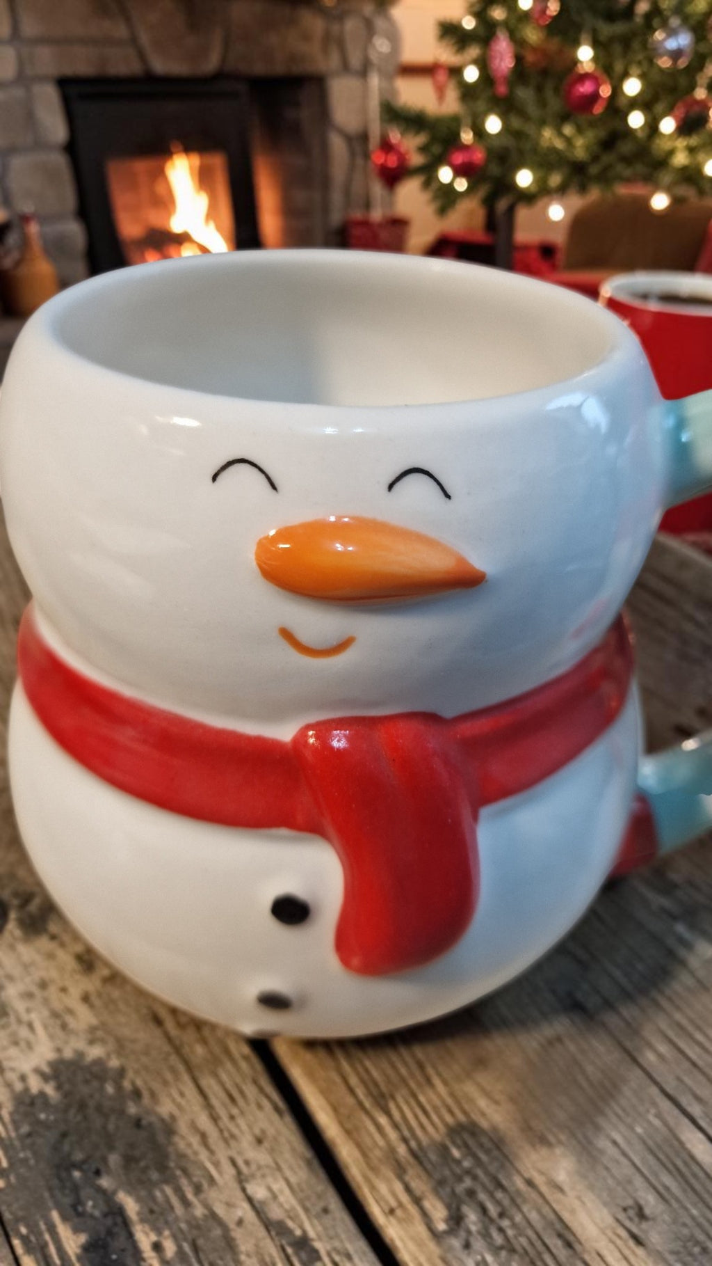 Snowman-shaped mug on a wooden surface with a Christmas tree in the background