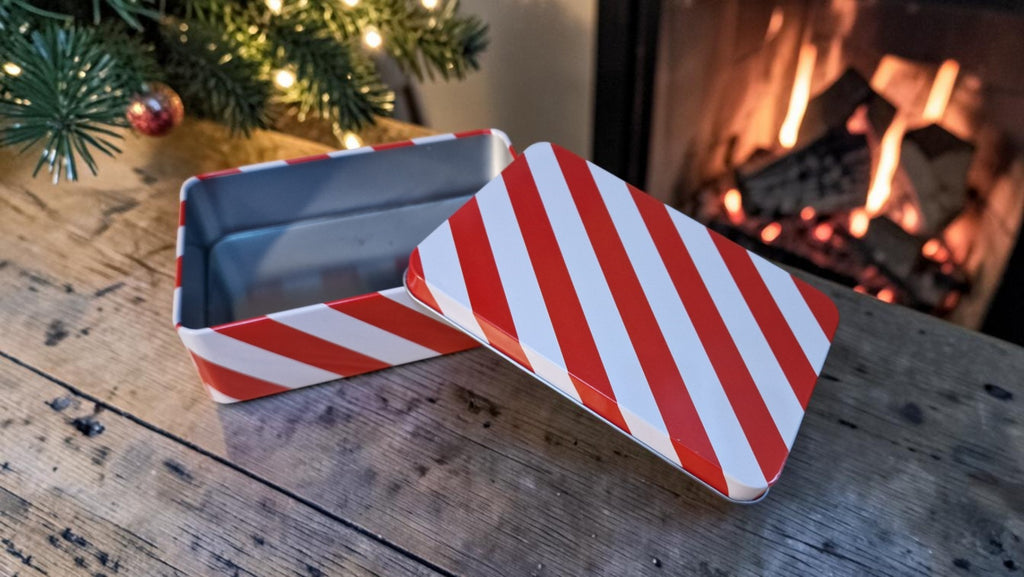 Red and white striped candy box on a wooden surface with a fireplace in the background