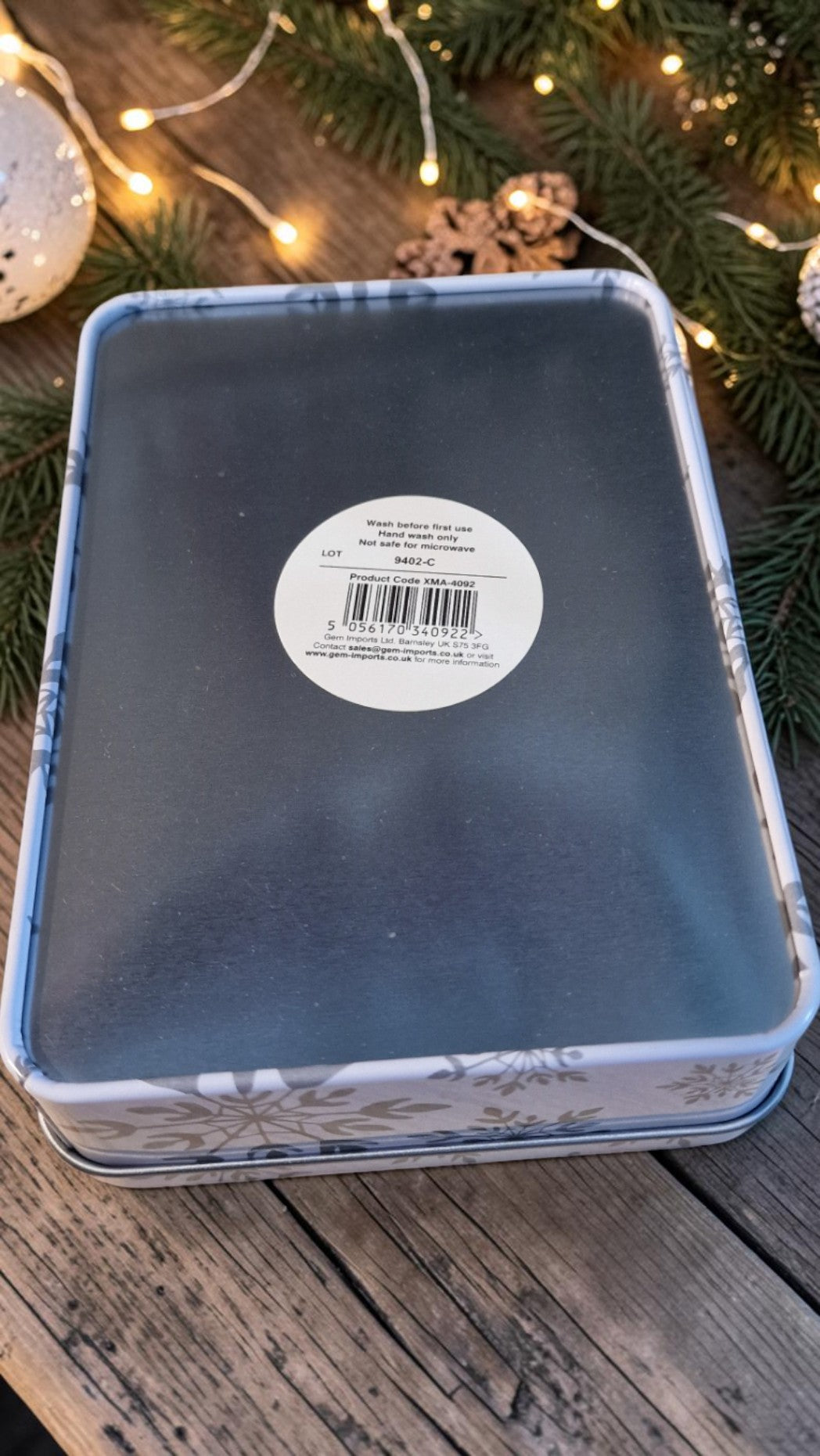 Blue tin box with a label on a wooden surface with Christmas decorations.