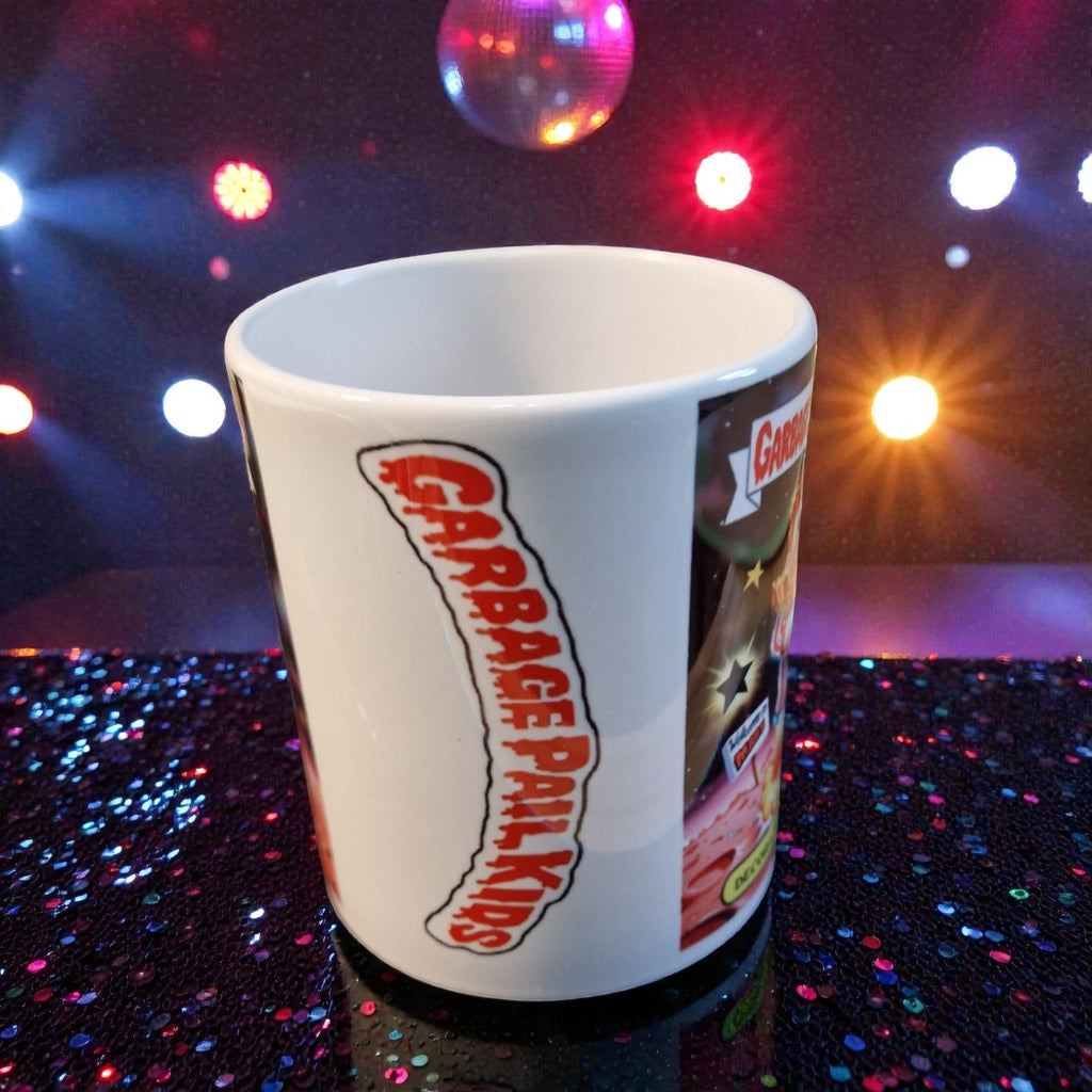 White mug with Garbage Pail Kids design on a glittery surface with disco lights.