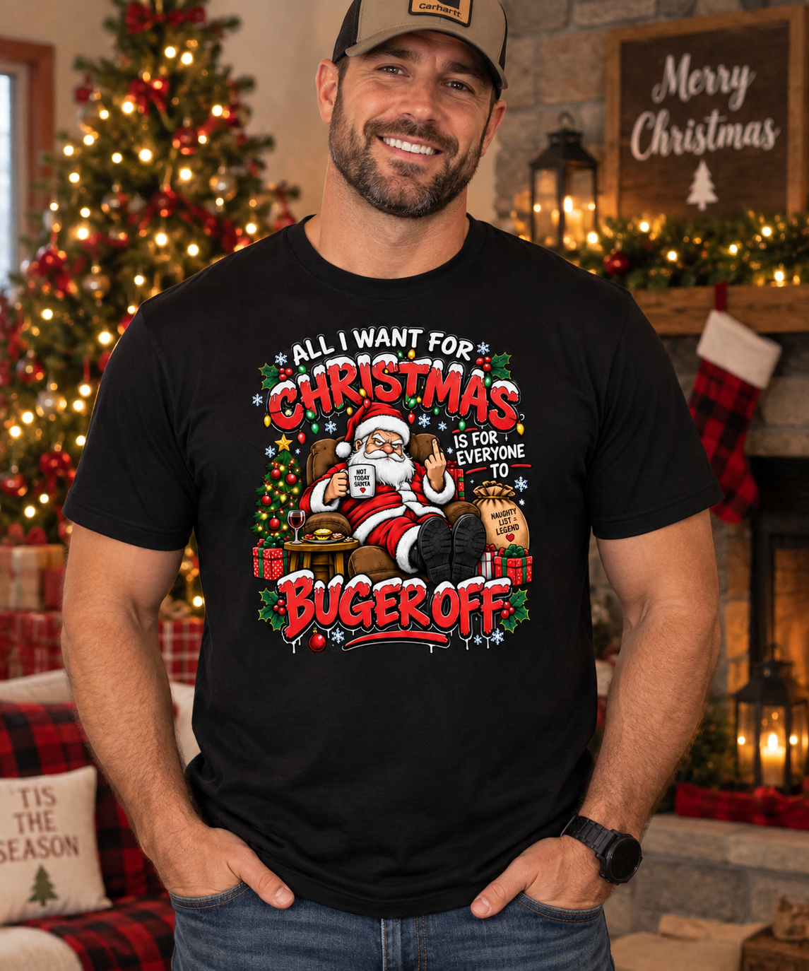 A man wearing a black graphic t-shirt with a festive Christmas design that reads 'ALL I WANT FOR CHRISTMAS IS FOR EVERYONE TO BUGER OFF', posed in a cozy holiday living room setting with a decorated Christmas tree and fireplace in the background.