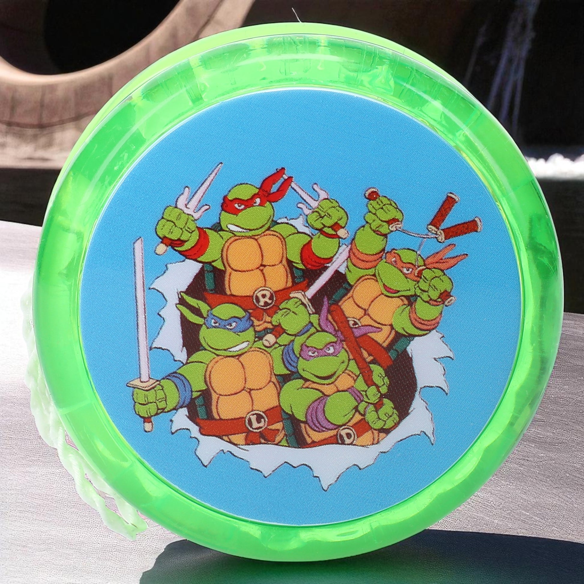 Green Nickelodeon Teenage Mutant Ninja Turtles light up yo-yo with all four TMNT characters on the front, glowing in the light.