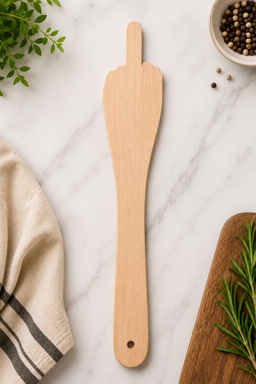 A wooden kitchen utensil shaped like a hand gesture is shown on a white marble surface with kitchen props including a folded cloth, peppercorns, and rosemary.