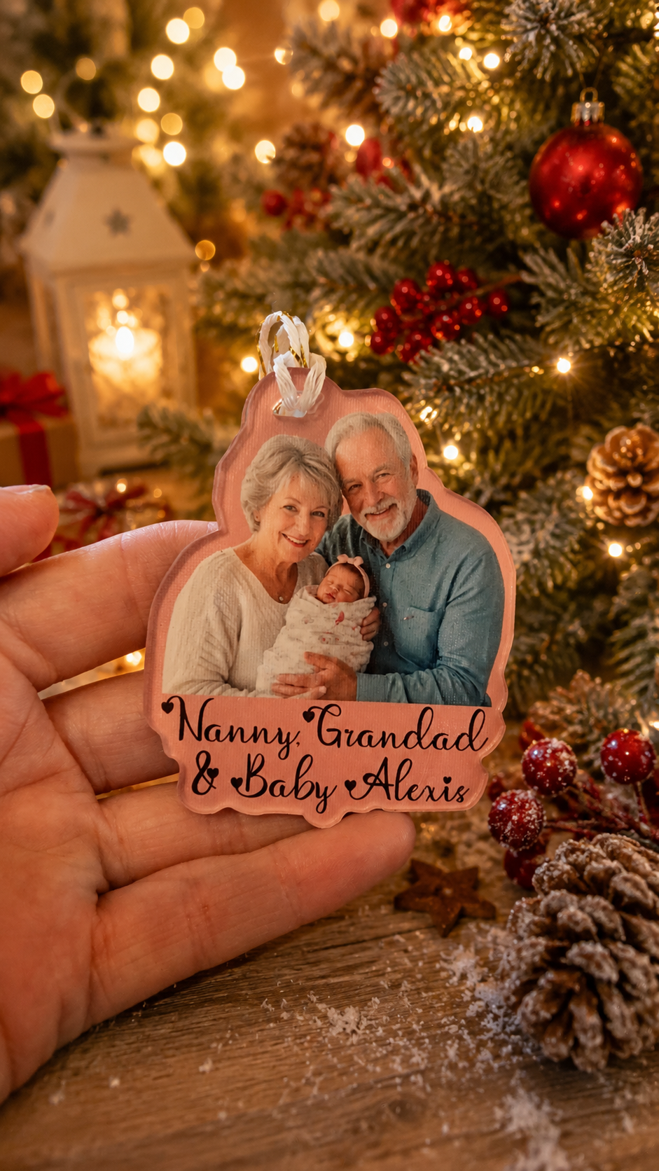 Hand holding a personalized Christmas ornament with an image of a family in front of a decorated tree.