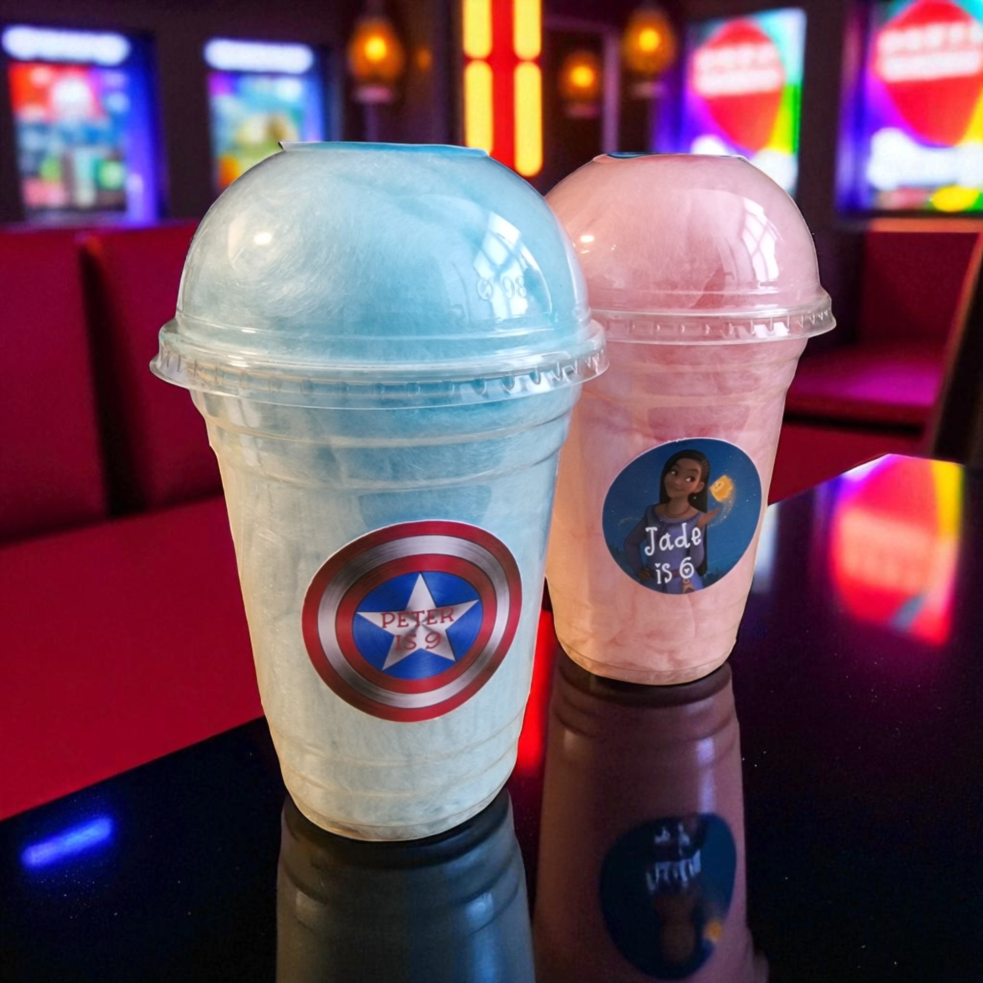Two colorful drinks in plastic cups with superhero and personalized labels, set against a vibrant background.