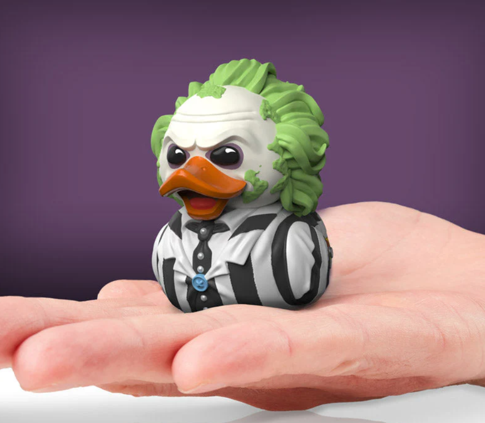 Toy duck dressed as a character with green hair and striped outfit held in a hand against a purple background