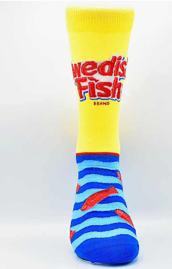 Swedish Fish socks and packaging on a wooden surface with neon lights in the background