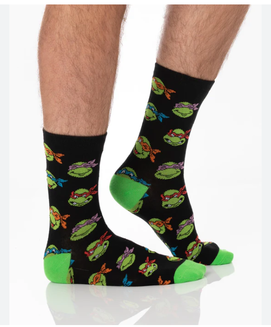 Black socks with green turtle pattern worn by a person on a white background