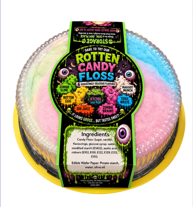 A packaged novelty candy floss cake on a yellow tray, with a colorful pastel floss topping and a black label reading 'Rotten Candy Floss' and 'Dare to try our Rotten Candy Floss'.