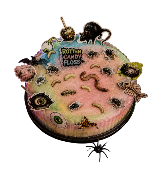 A round novelty cake or dessert topper with a Halloween theme, featuring pink frosting, fake worms, spiders, a rat, a fish skeleton, a eyeball, and the text 'ROTTEN CANDY FLOSS' on a white background.