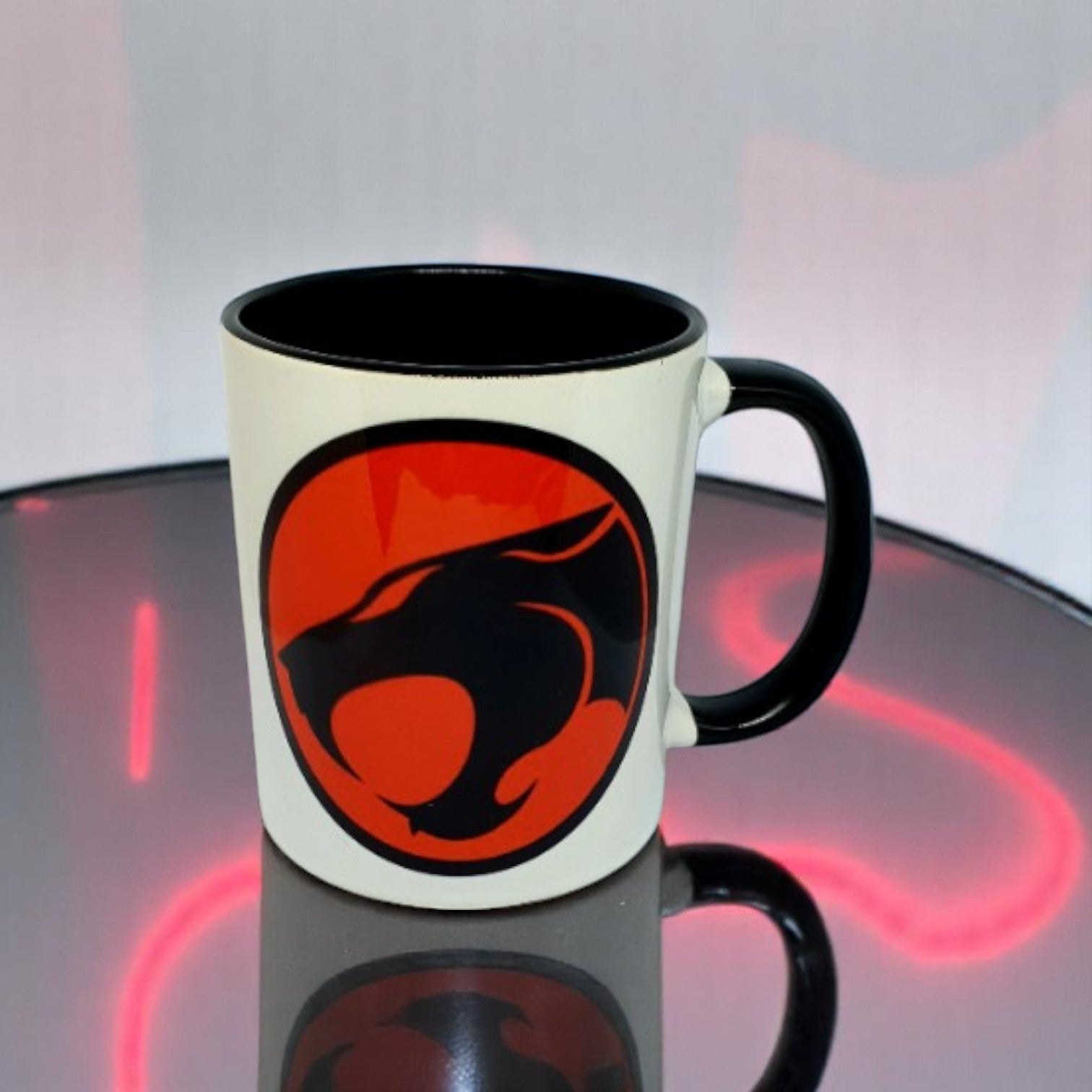 Mug with a red and black logo on a reflective surface