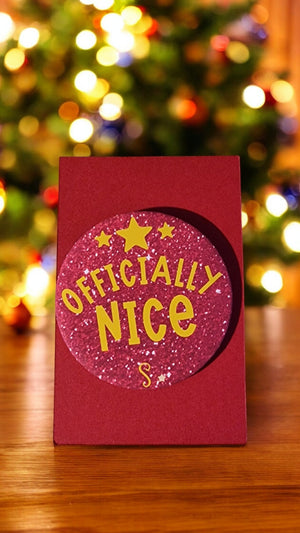 Red card with 'Officially Nice' text in front of a Christmas tree