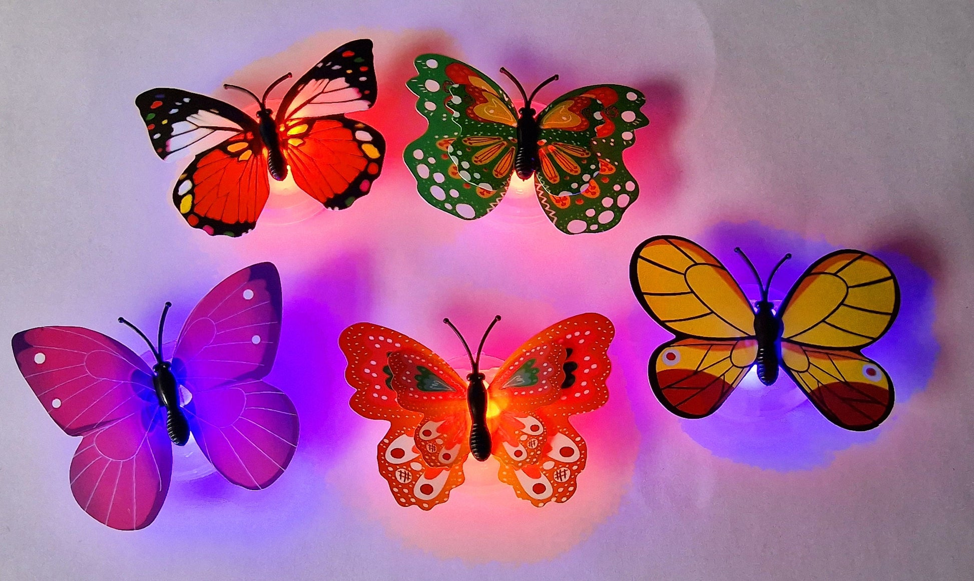 Set of five colourful butterfly LED night lights flashing on a wall, shown as fun party and room decor.