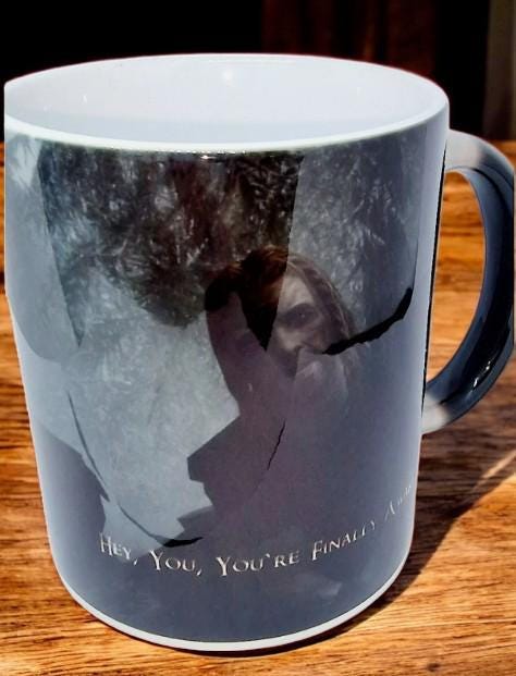 Black color change mug with “Hey you’re finally awake” Ralof design revealed by heat, shown as a fun gamer and coffee lover gift.
