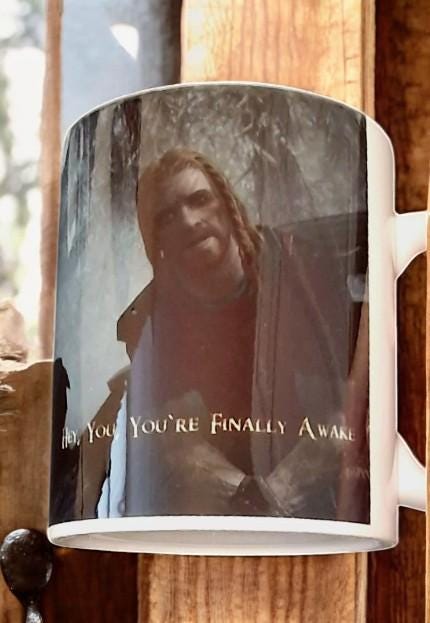 Black color change mug with “Hey you’re finally awake” Ralof design revealed by heat, shown as a fun gamer and coffee lover gift.