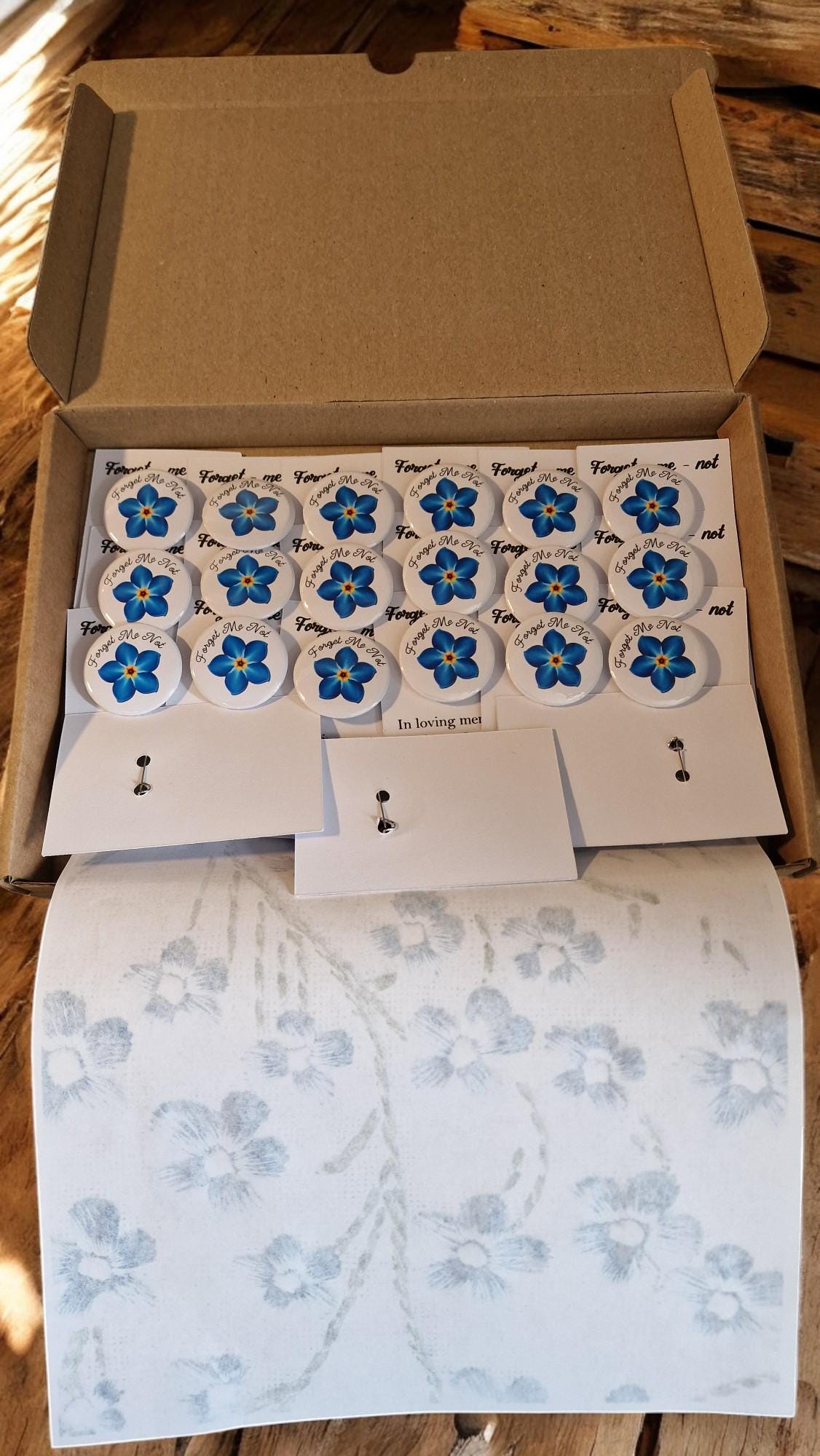 Set of 20 forget me not funeral badges on personalised “In Loving Memory” cards, displayed as keepsake mementos for funerals or dementia remembrance.