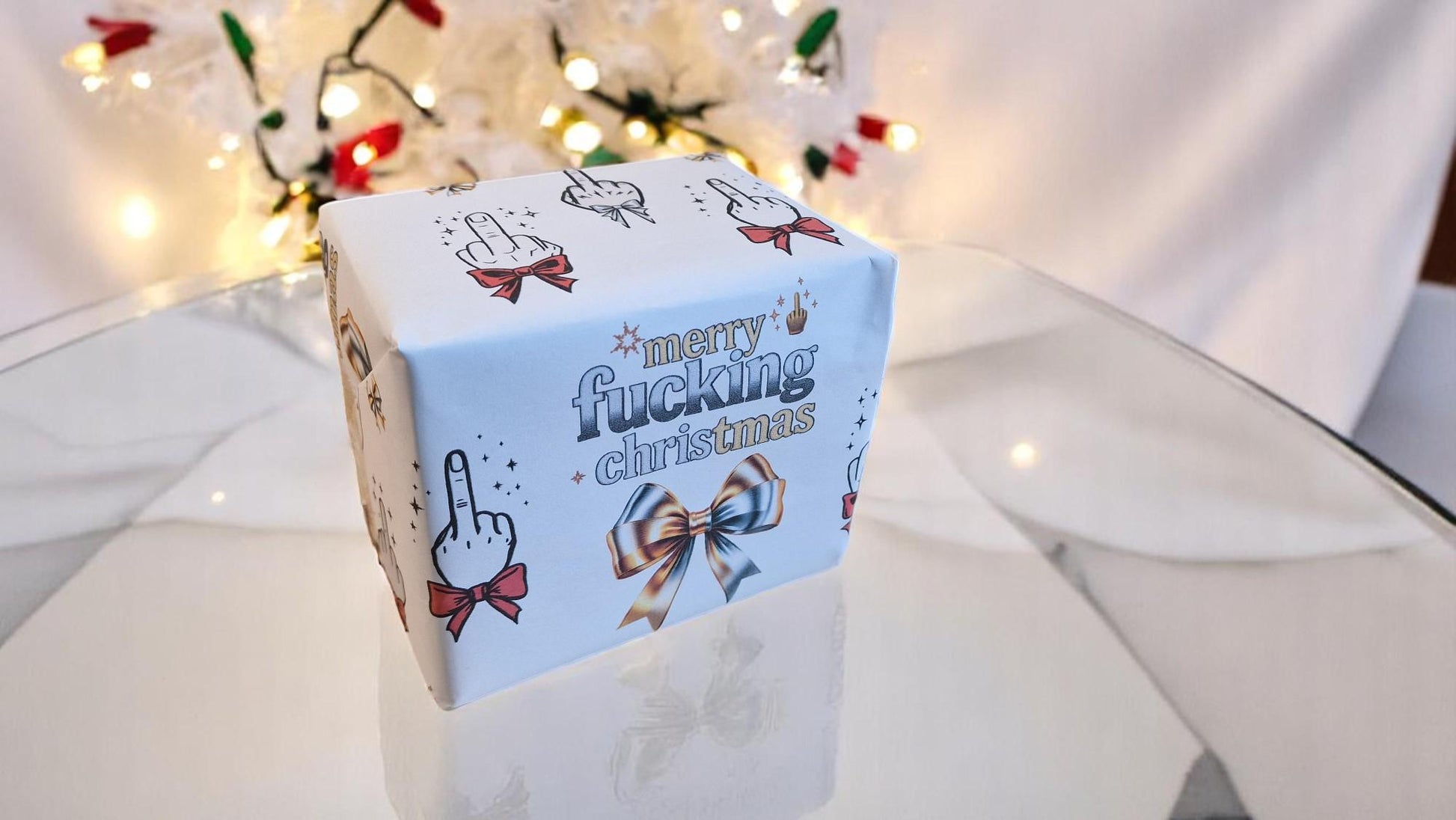 Two sheets of Merry Fucking Christmas wrapping paper with a cheeky middle finger design, displayed as funny Secret Santa gift wrap.