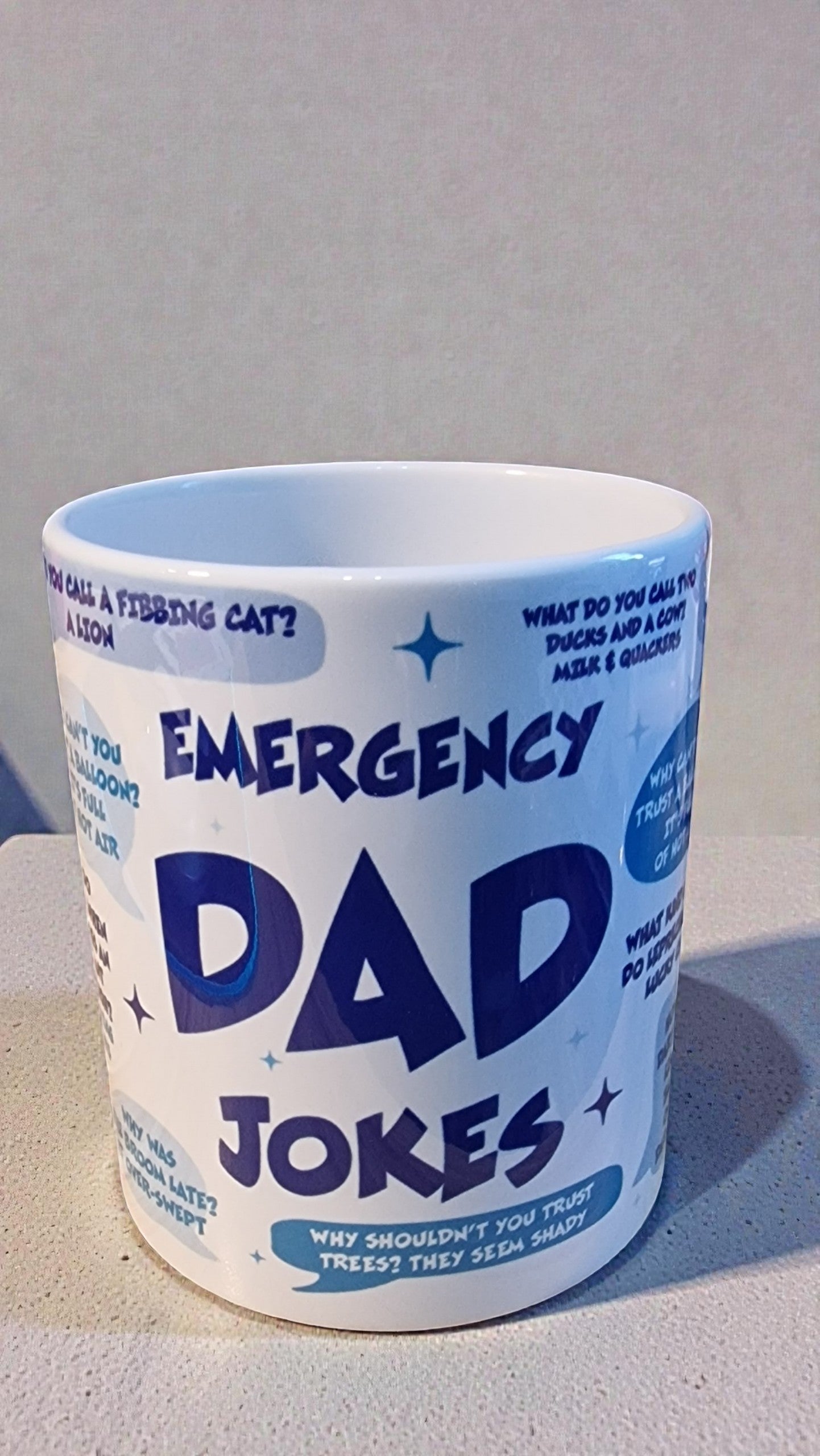 Mug with 'Emergency Dad Jokes' text on a plain background
