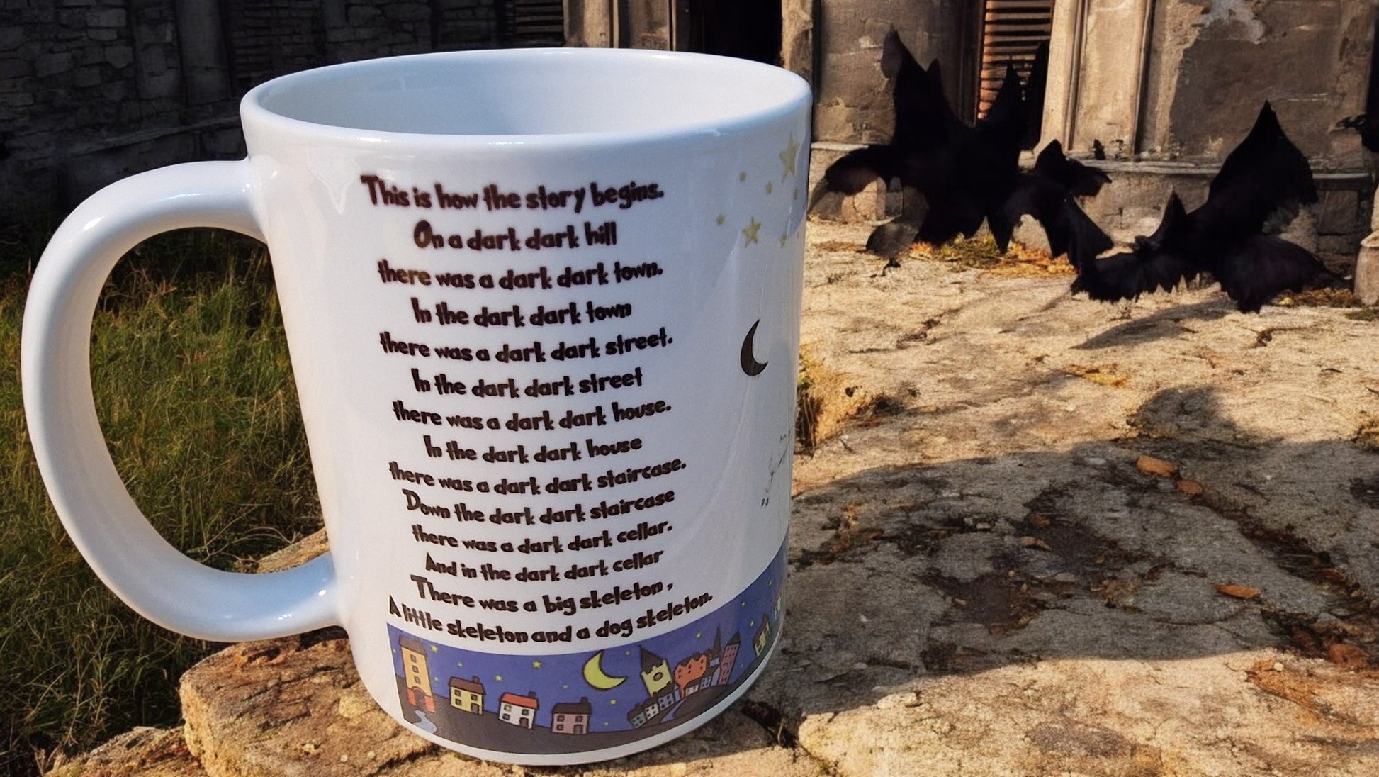 Mug with a story printed on it, placed on a stone surface with bats in the background