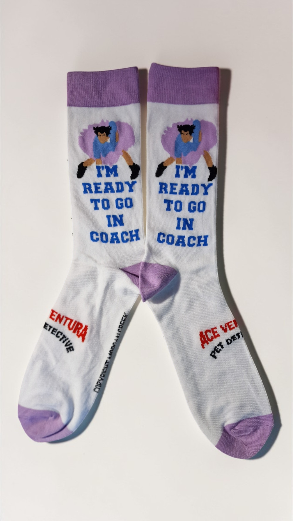 White socks with purple accents featuring cartoon character and text on a light gray background