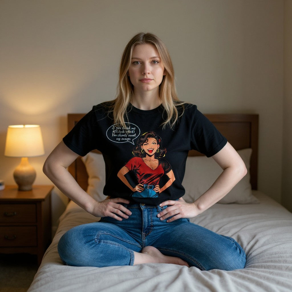 Woman sitting on a bed wearing a black t-shirt with a graphic design.