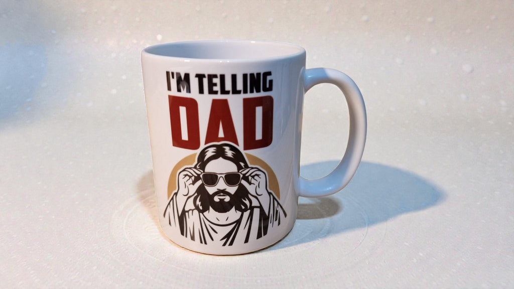 White mug with text 'I'm Telling Dad' and a graphic of a person wearing sunglasses on a white background.