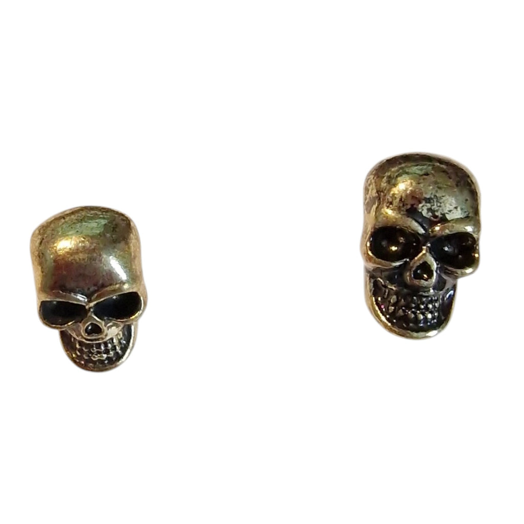 A pair of antique bronze skull stud earrings on a plain white background.