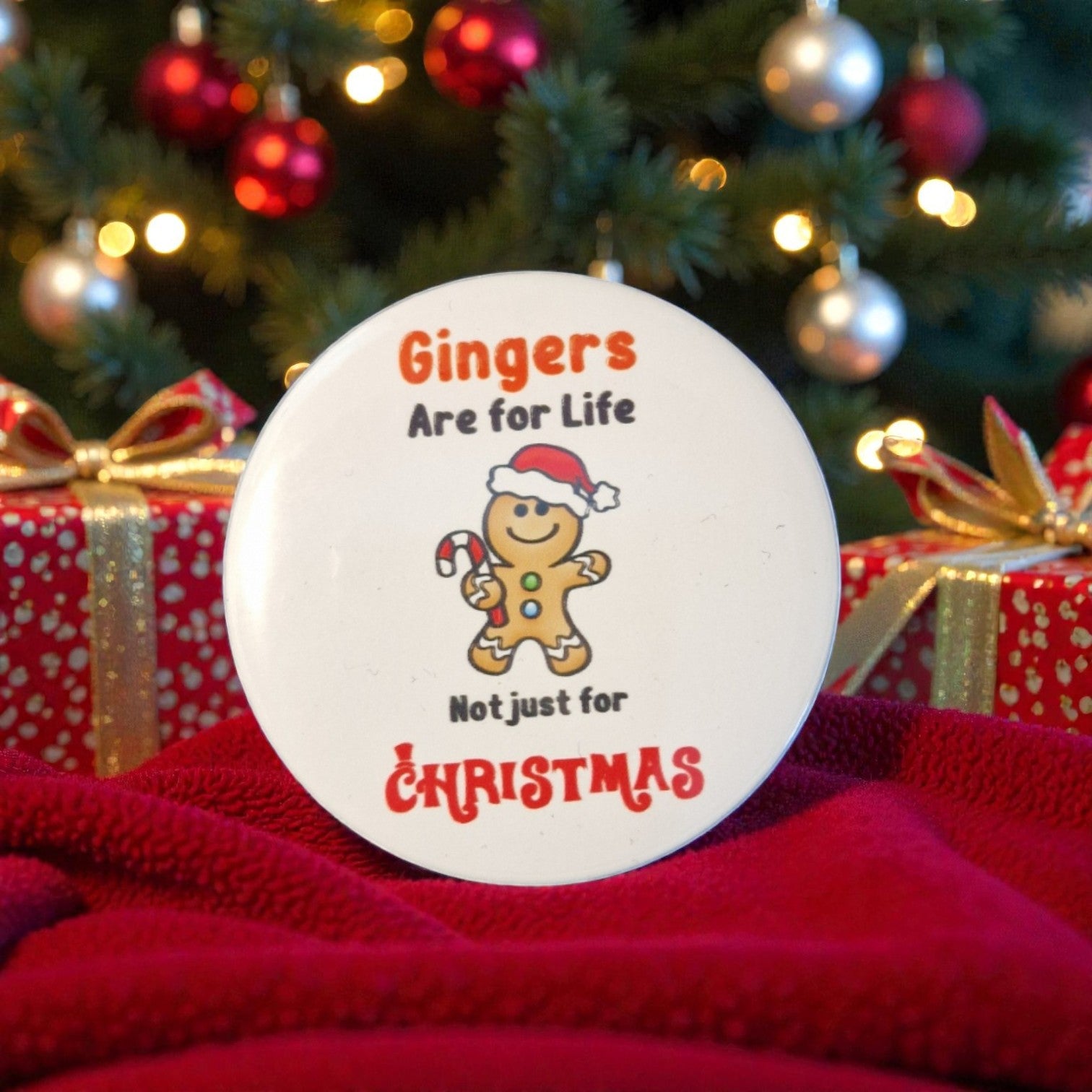 Decorative plate with gingerbread man and text in front of a Christmas tree and presents.