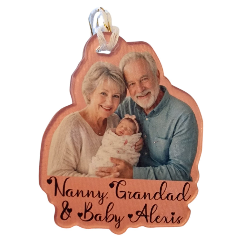 Personalized ornament with a photo of an older couple holding a baby, labeled 'Nanny, Grandad & Baby Alexis'.